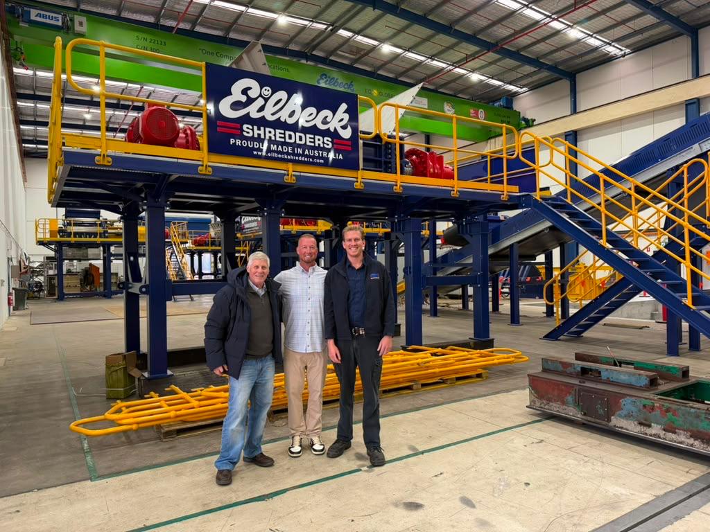 Three people stand in front of the finished shredding line in the Ingleburn workshop