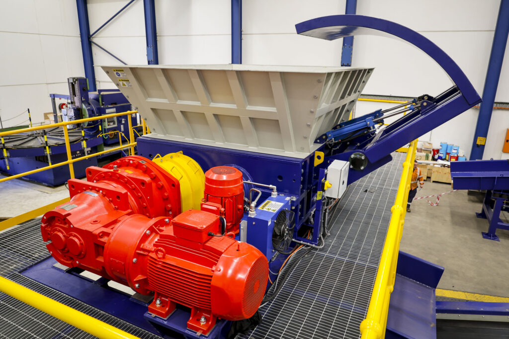 A blue dual-shaft shredder with red drives on the workshop floor