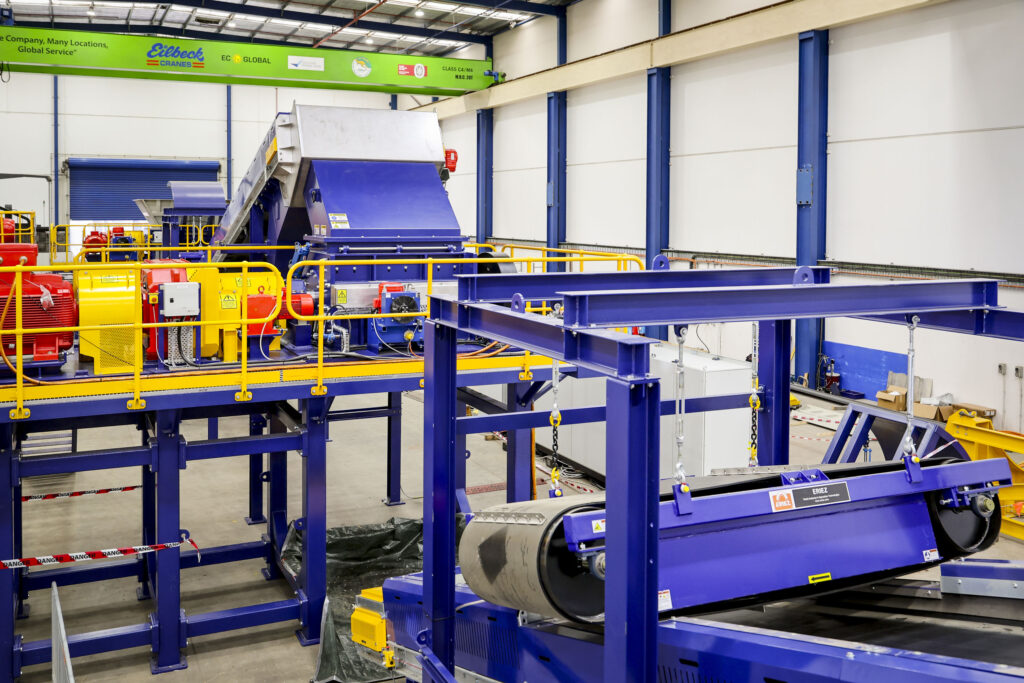 A blue Eilbeck shredding plant with conveyors and a magnetic separator in the workshop